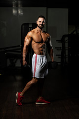Fototapeta na wymiar Bodybuilder Exercising Biceps With Dumbbells