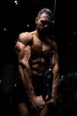 Fototapeta na wymiar Bodybuilder Doing Heavy Exercise For Triceps With Cable