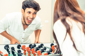 Happy couple playing foosball table.