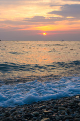 Obraz premium Amazing sea sunset on the pebble beach, the sun, waves, clouds