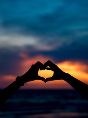 Hand making keep love and heart shape with sunset silhouette ,copy space,warm retro tone.