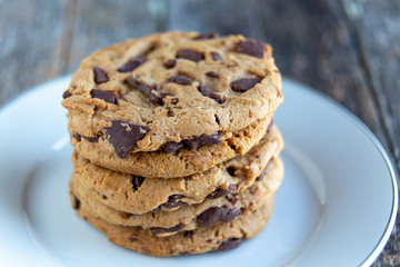Stacked chocolate chip chunk cookies on white plate