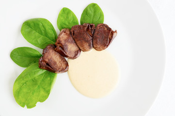 fried offals starter with spinach leafs and gravy sauce