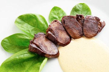 turkey hearts appetizer with spinach leafs and gravy sauce