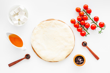 Ingredients for cooking vegetarian pizza. Rolled pizza dough, cherry tomatoes, olive oil, cheese mozzarella, spices on white background top view mockup