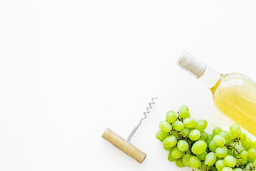Open the wine concept. White wine in glass bottle near bunch of grapes and corkscrew on white background top view copy space
