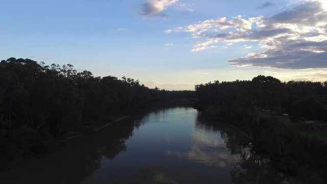 Drone ascending over The Murray River, New South Wales Australia, during sunset reveal blue sky with clouds.