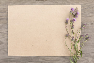 Purple wildflowers with handmade craft notebook on old grunge wooden background. Top view. Minimalistic mockup.