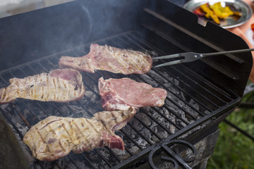 horizontal image with the hands of the man who is cooking grilled meat, during a barbecue