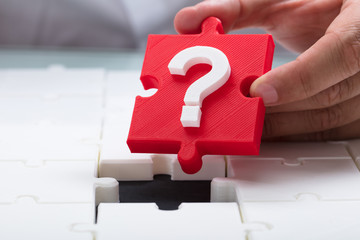Person placing question mark piece into jigsaw puzzle
