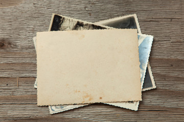 Stack old photos on table. Mock-up blank paper. Postcard rumpled and dirty vintage