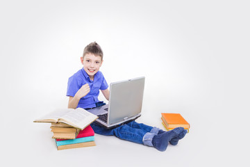 Portrait of cute teen schoolboy sitting near books and typing on laptop keyboard. Happy and surprised little boy, caucasian model isolated on white studio background. Education, study, studying