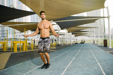 Young arab sports man exercising with jump-rope outdoors in Dubai during summer time.