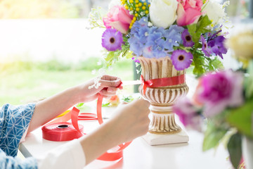 young women business owner florist making or Arranging Artificial flowers vest in her shop, craft and hand made concept