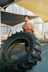 Fototapeta na wymiar Young arab sports man exercising with truck tyre outdoors in Dubai during summer time.