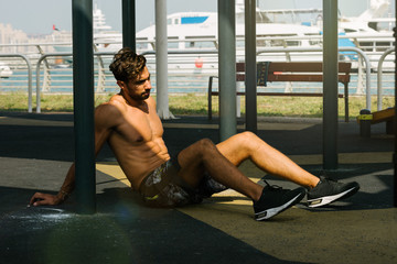 Portrait of a young arab sports man have a rest after push ups exercise on horizontal baroutdoors in Dubai during summer time.