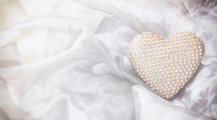 Golden sequin heart, top view, copy space, on a white silky tulle background.
