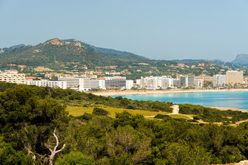 Obraz premium View to the beach of Cala Millor with the hotels and beach promenade with the hills and mountains in the background on the Spanish Mediterranean island Mallocra