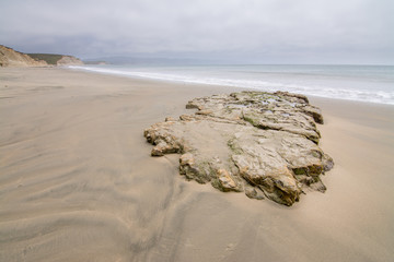 Rock on sandy shore of ocean