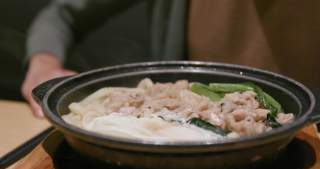 Woman eating bowl of udon in restaurant