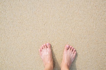 Close Up of a man's bare feet stand at wet on the beach , with a sand edge gently beneath them. Vacation on ocean beach, foot on sea sand. Leave empty copy space Enter the text above.