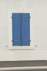 Closed blue wooden blinds on a white wall