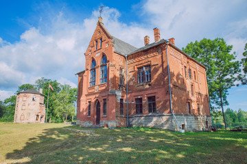 Old manor house and meadow, green trees. Travel photo 2018.