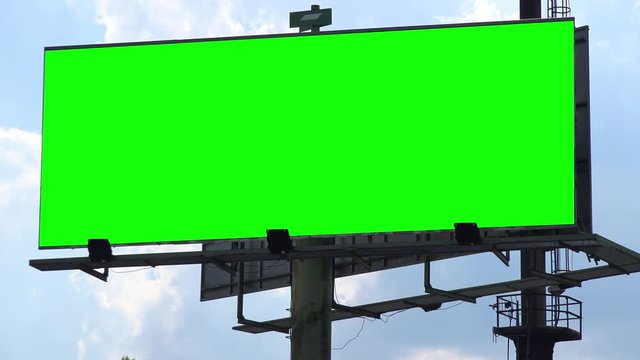 A billboard with a green screen against the blue sky - view from below