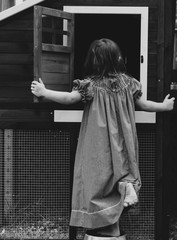 Toddler Child in country dress looking in chicken coop