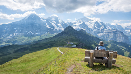 Fototapeta na wymiar Wanderer auf der Rastbank, genießt die atemberaubende Aussicht auf die Schweizer Alpen