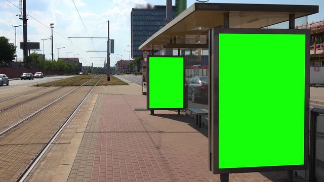 Green screens on the sides of a tram stop in an urban area