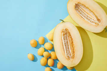 top view of fresh sweet apricots and halved melon on blue and yellow background
