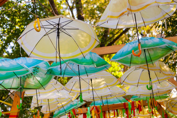 Concept shot of umbrellas of different colors in the air in park.  Many of the larger size hanging umbrellas.