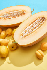 close-up view of fresh ripe halved melon, lemons, apricots and pear on blue and yellow