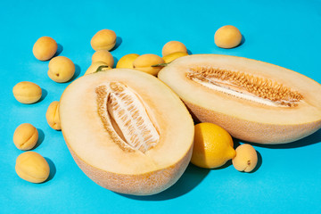 close-up view of ripe sweet halved melon and lemons with apricots on blue