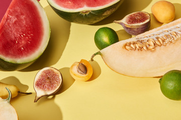 close-up view of sweet ripe watermelon, melon, limes, figs and apricots on yellow