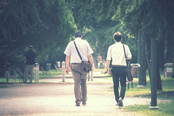 background image of walking businessmen, one of them holds a book in his hand