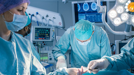 Diverse Team of Professional Surgeons Performing Invasive Surgery on a Patient in the Hospital...