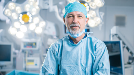 Portrait of the Professional Surgeon Looking Into Camera and Smiling after Successful Operation. In the Background Modern Hospital Operating Room. - obrazy, fototapety, plakaty