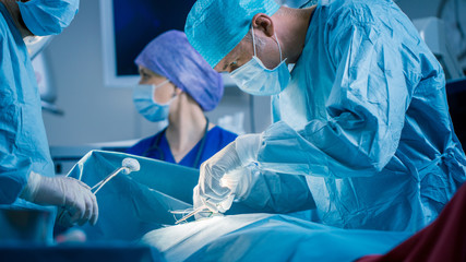 In the Hospital Operating Room Diverse Team of Professional Surgeons and Nurses Suture Wound after...