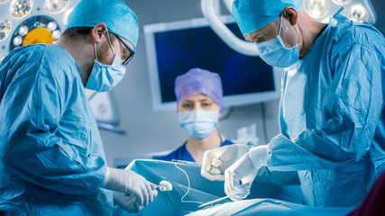 In the Hospital Operating Room Diverse Team of Professional Surgeons and Nurses Suture Wound after Successful Surgery.