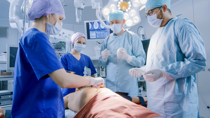 In the Hospital Operating Room Anesthesiologist Applies Anesthesia Mask to a Patient, Assistants...