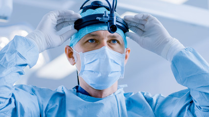 In the Hospital Operating Room Professional Surgeon Puts on Surgical Flashlight, Before Surgery...