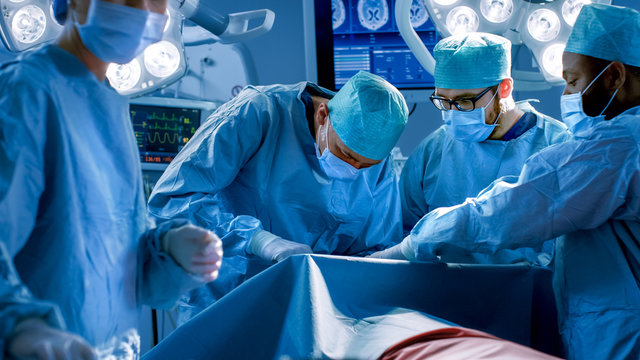 Diverse Team of Professional surgeon,  Assistants and Nurses Performing Invasive Surgery on a Patient in the Hospital Operating Room. Real Modern Hospital with Authentic Equipment.