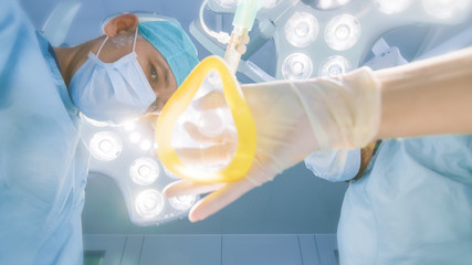 Low Angle Shot POV Patient View: Two Professional Surgeons Holding Surgical Instruments Ready to...
