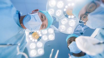 Low Angle Shot POV Patient View: Two Professional Surgeons Holding Surgical Instruments Starting...