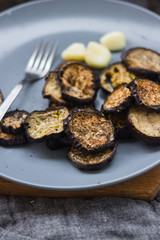 Crust roasted eggplants slices on stylish grey plate. Sprinkled with herbs, black pepper and garlic powder. Perfect vegan dish without refined oil. Delicious vegetarian lunch. Vegetables small portion