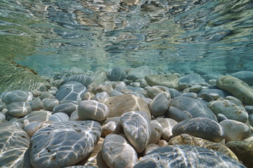 Pebbles and rocks below water surface in shallow water in the Mediterranean sea, underwater scene,...