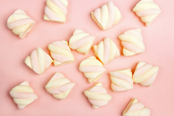 Colorful spiral marshmallows on pink background.