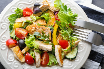 Plate with tasty chicken salad on table